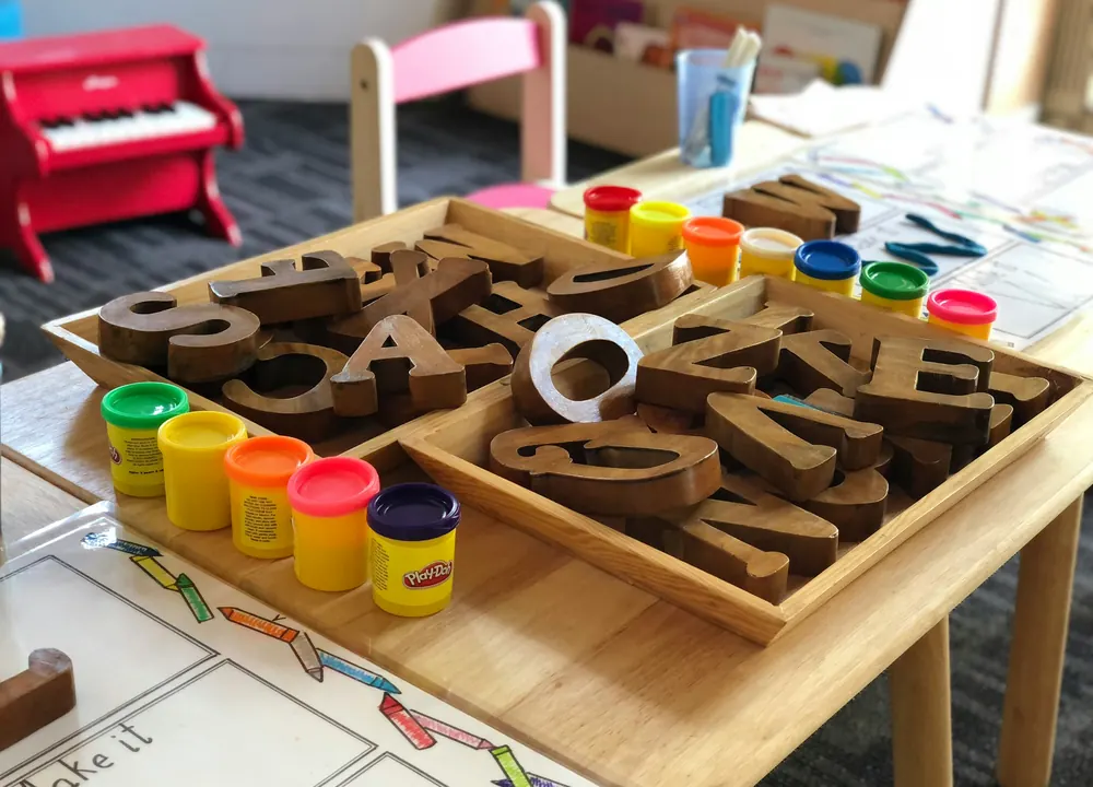 A wooden letter tray and pots of paint set out on a table
